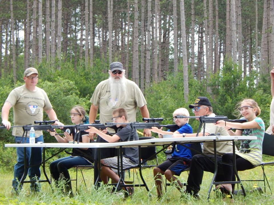 group of youth and instructors practice at the shooting range