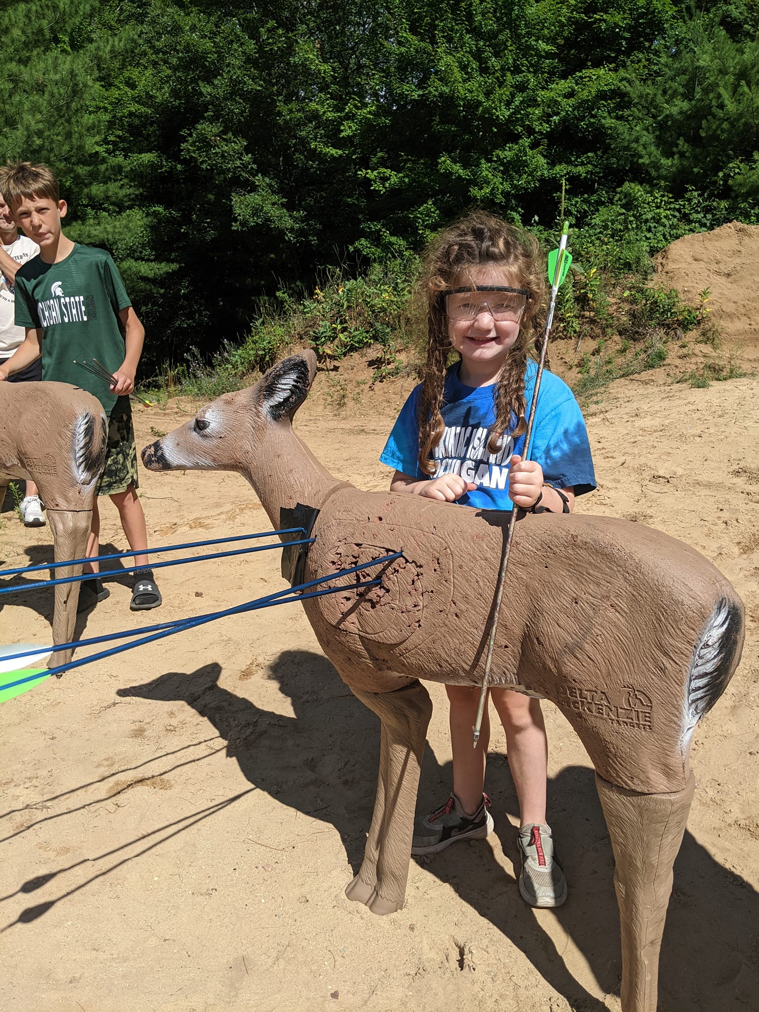 young archer stands proudly near her deer decoy target