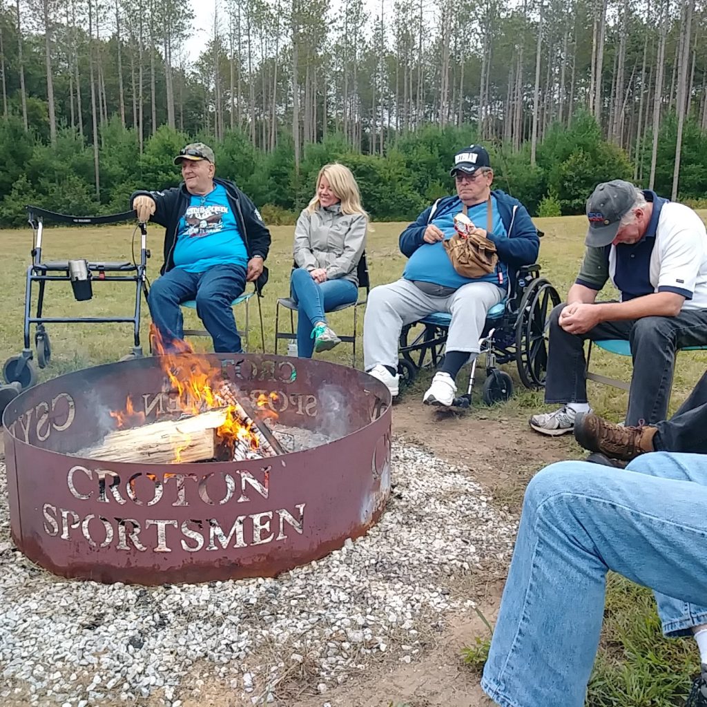 a group of veterans sit and converse around a campfire at the croton facility