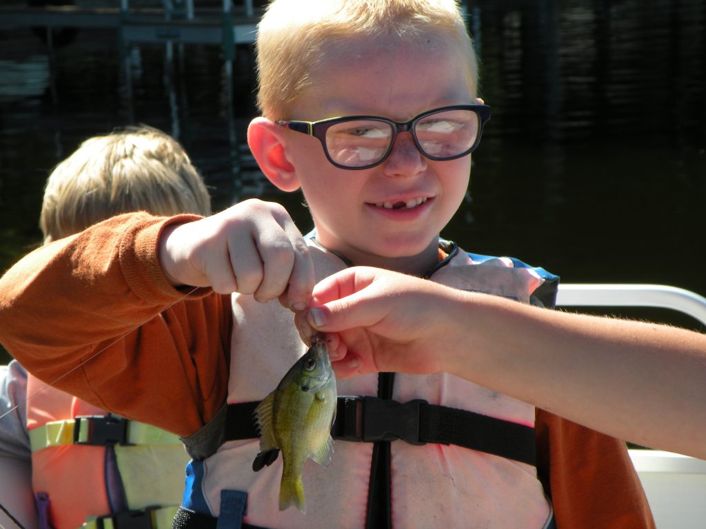 youth fisherman proudly holds up his catch